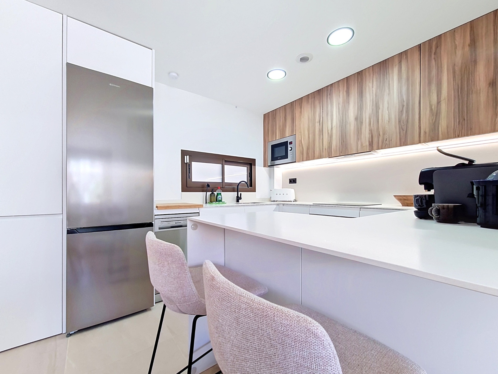 Kitchen with tall fridge-freezer and breakfast bar stools