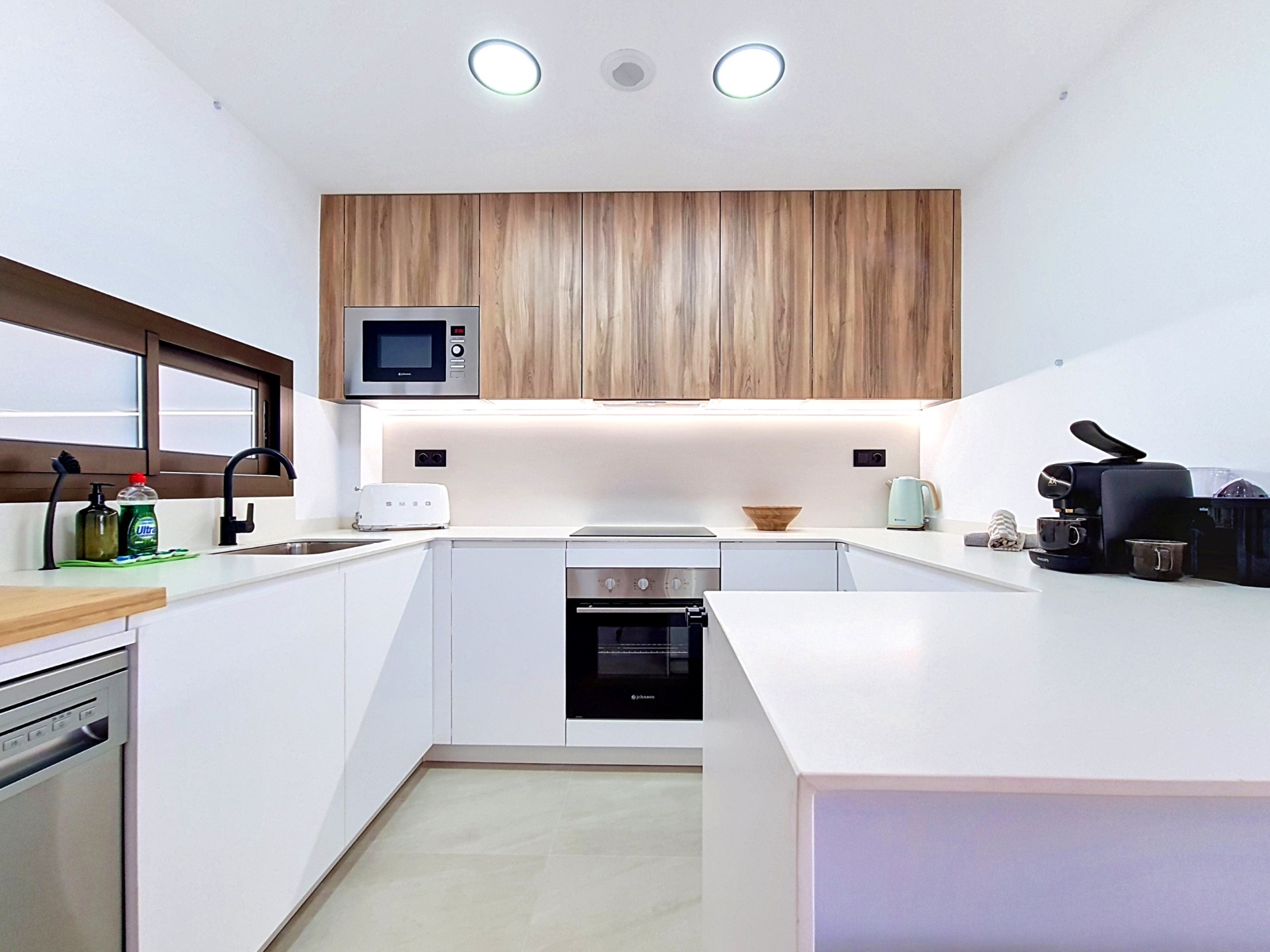Minimal white kitchen with wood cabinetry and coffee machine