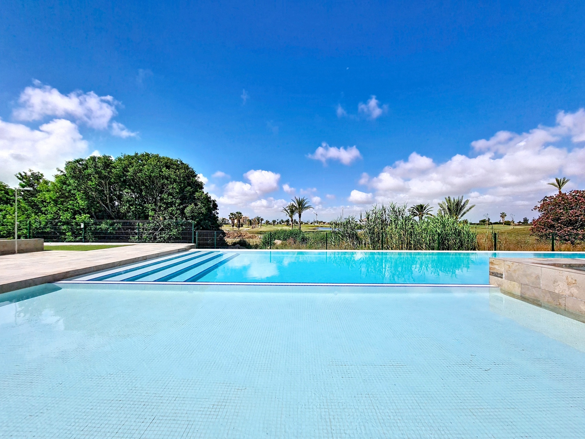 Infinity-style pool with golf course views beyond the water